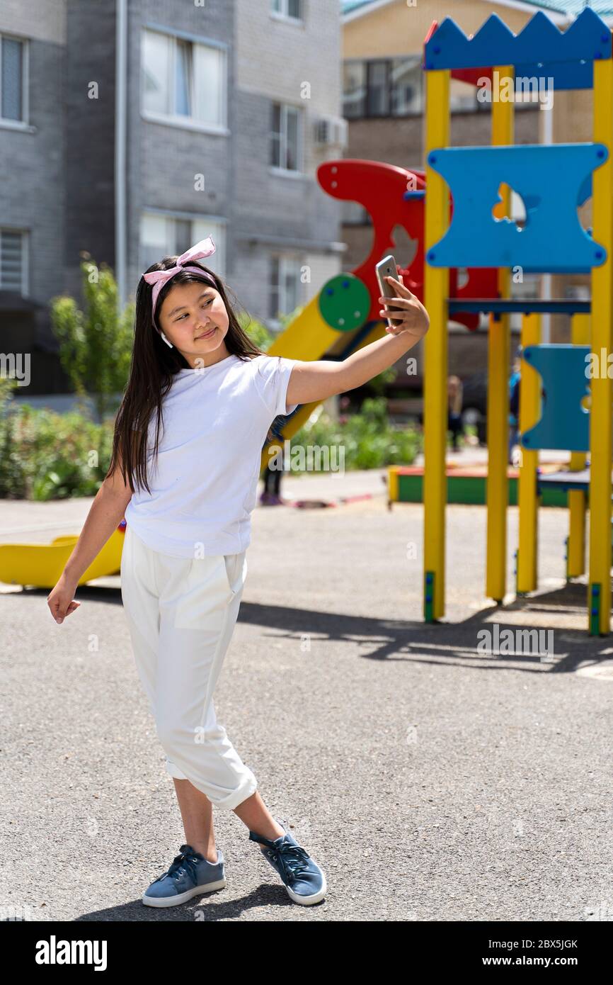 Schöne asiatische Mädchen mit Telefon auf der Straße. Stockfoto