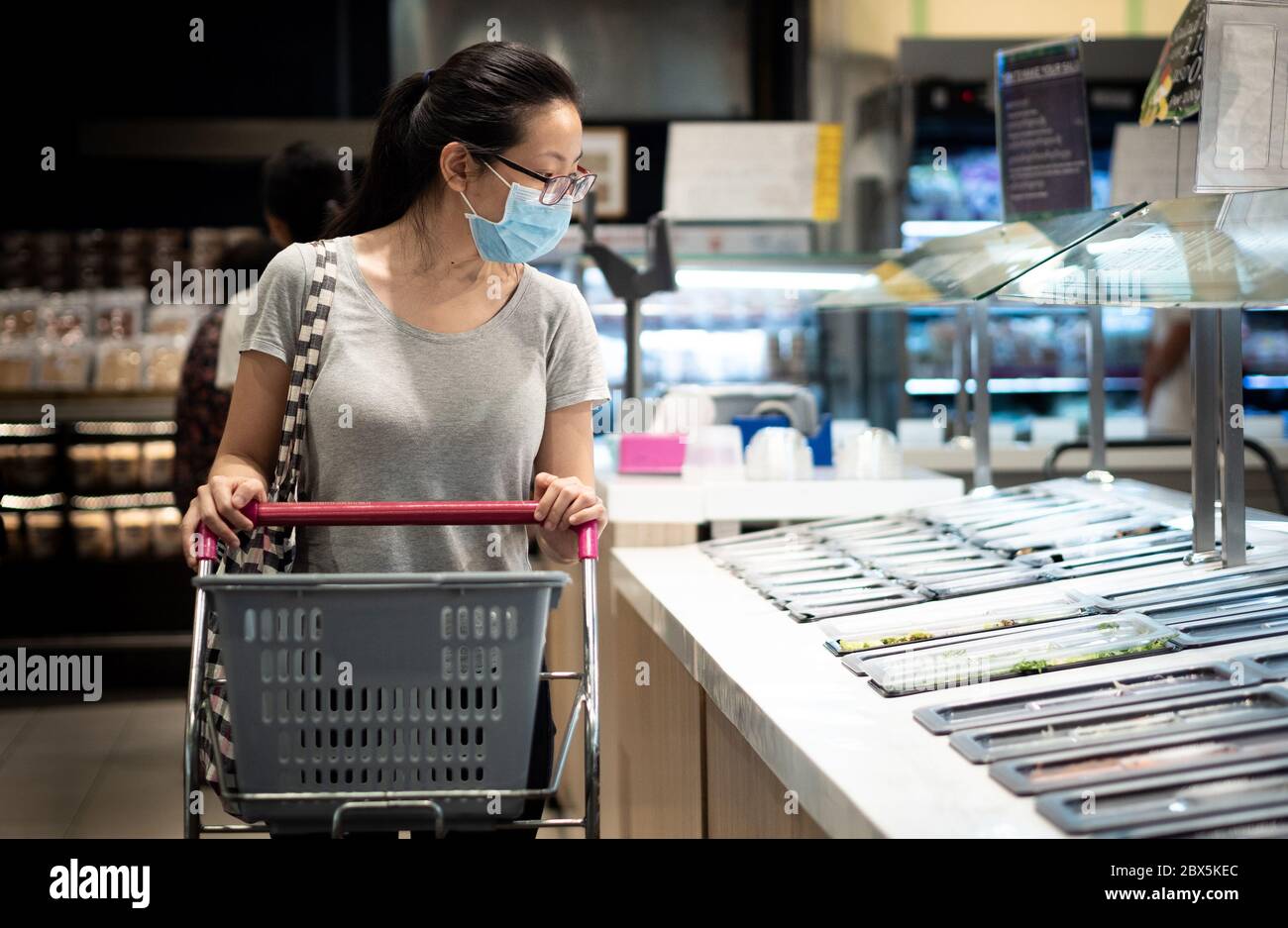 Neue normale, junge Frauen tragen Gesichtsmaske Lebensmittel Einkaufen in der Mall während Coronavirus Pandemie Krise. Stockfoto