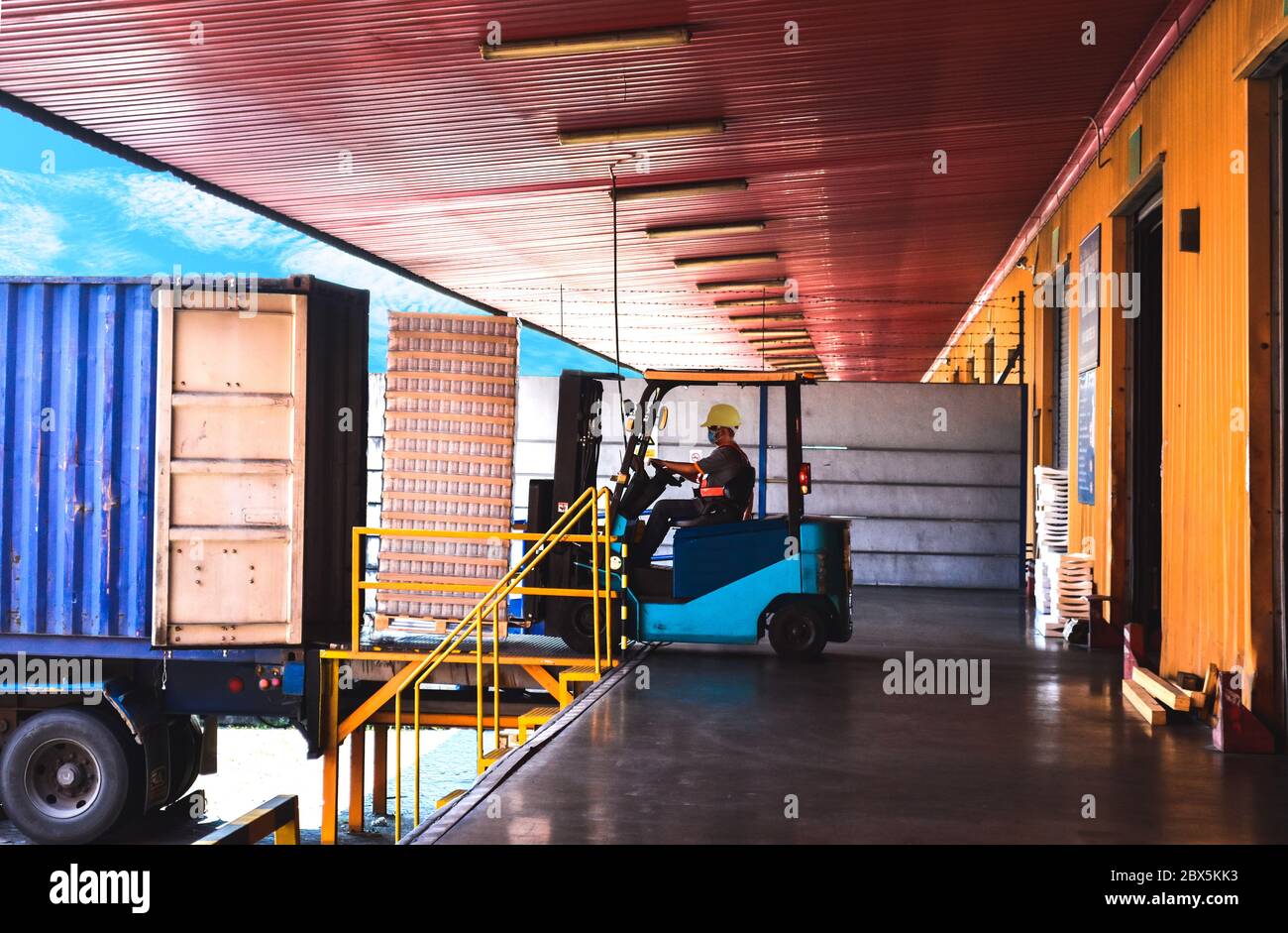 Container entfüllend, Gabelstapler transportiert Paletten der Ladung von Container in Lager zu setzen. Gabelstapler, Fahrer, Paletten von Fracht und Container auf LKW. Stockfoto
