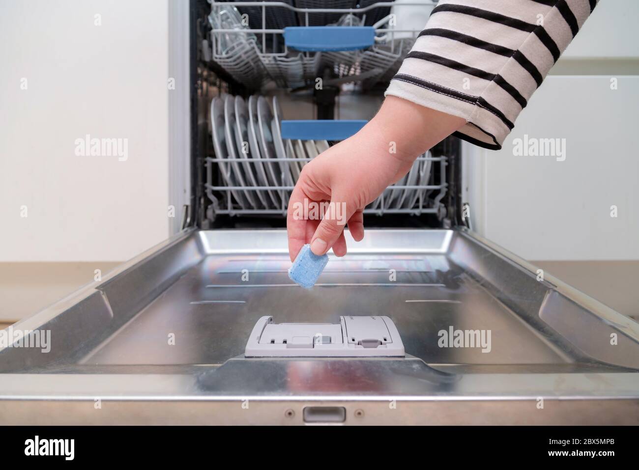 Nahaufnahme der Hand, die Seifenkapsel in die Spülmaschine in der Küche  einführt. Person, die Spülmittel in die Maschine einlegt Stockfotografie -  Alamy