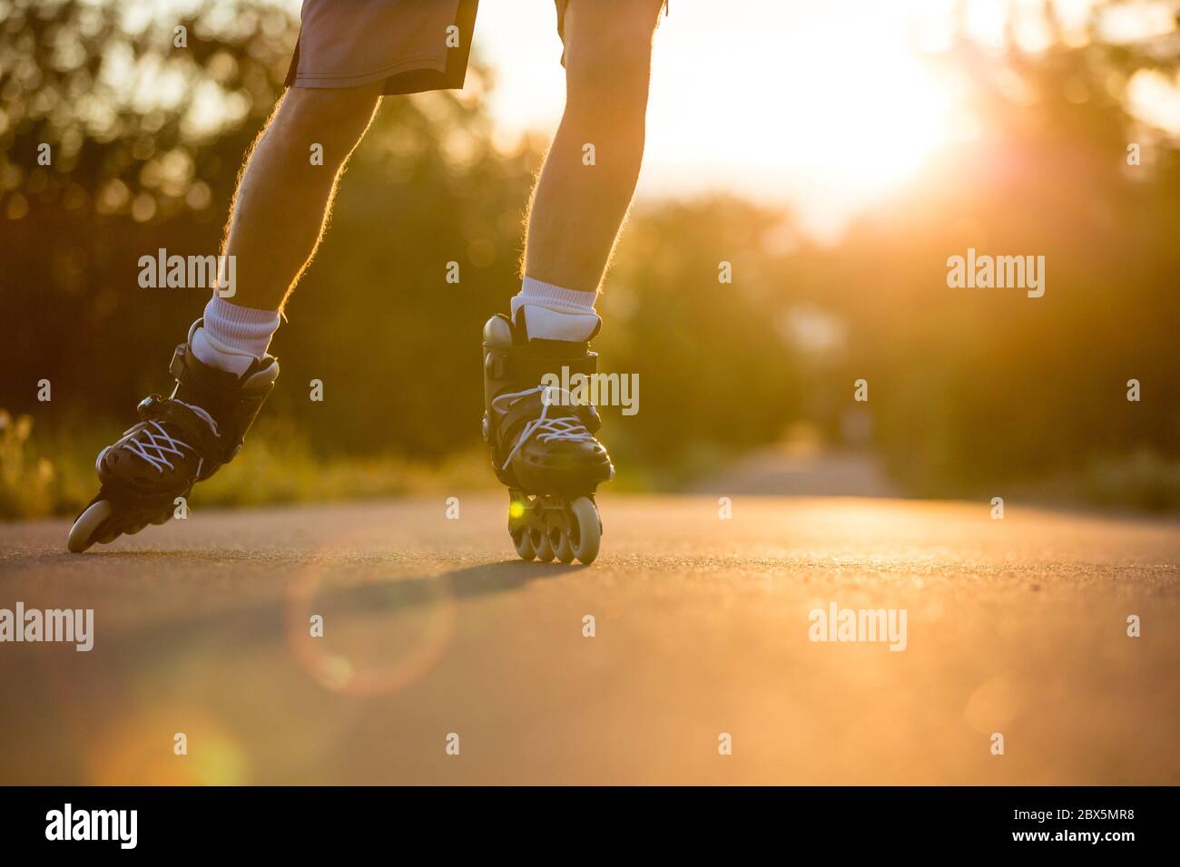 Junger Mann genießen Rollschuh auf dem Radweg während der schönen Sommer Sonnenuntergang, Lifestyle und Sport-Konzept Stockfoto