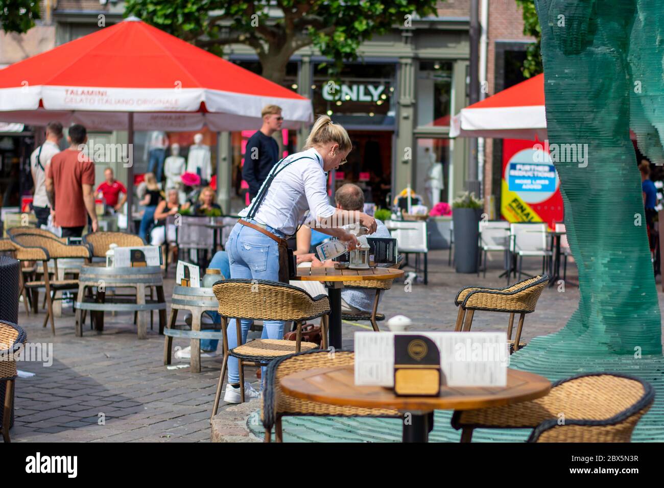 Zwolle, Niederlande. Kellnerin reinigt einen Tisch auf der Restaurantterrasse mit Desinfektionsmittel Alkohol Spray. Die Terrassen durften wieder geöffnet werden Stockfoto