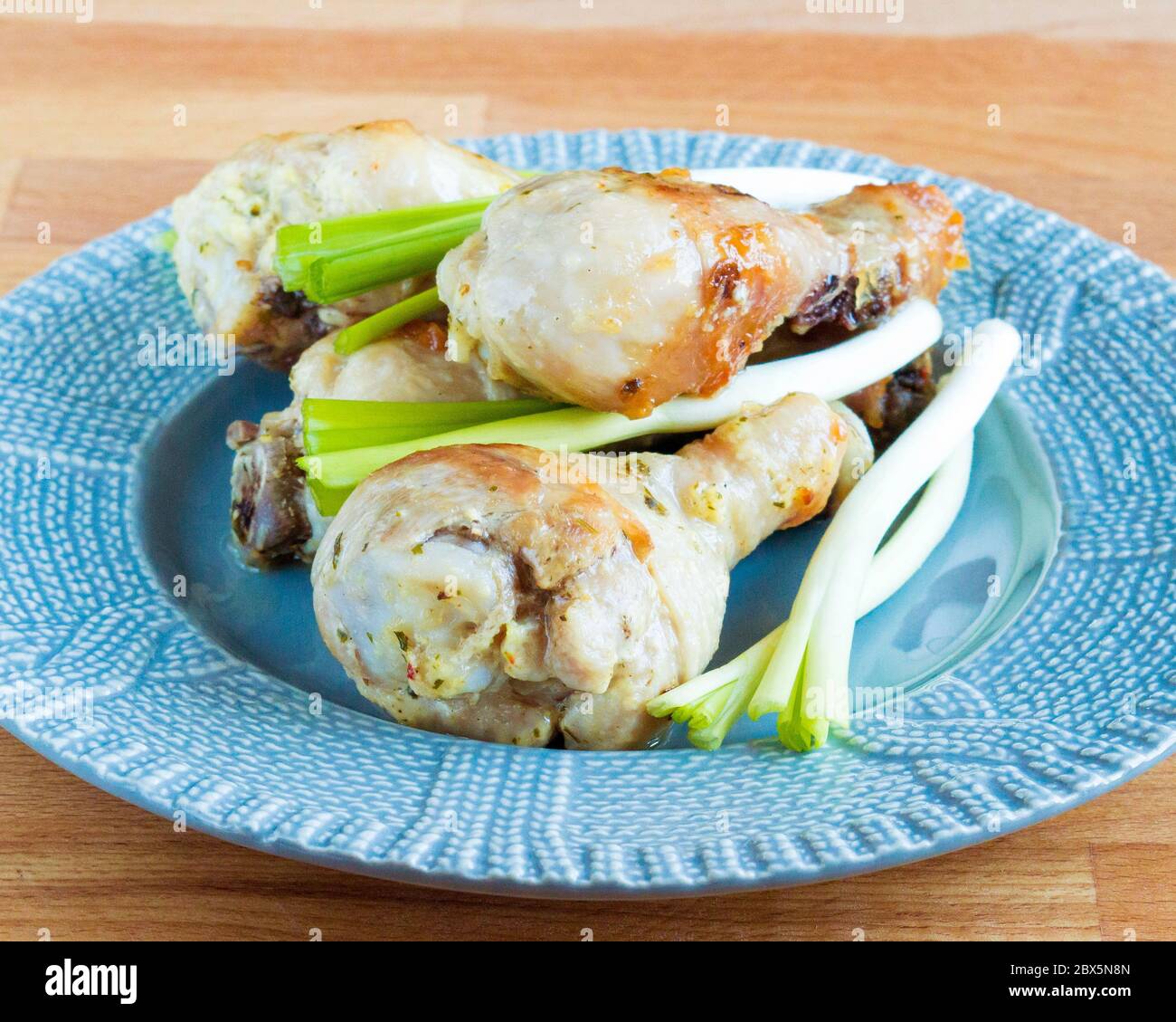 Appetitliches Huhn mit grünen Zwiebeln. Gebratenes Hähnchenschlagstock auf einem Teller. Serviert Gerichte. Stockfoto