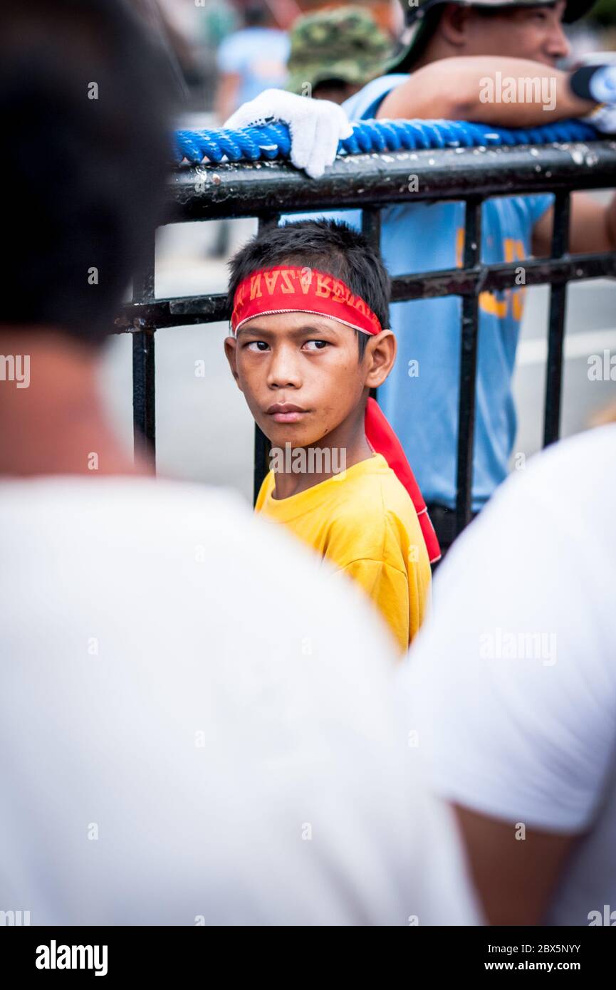 Ein kleiner philippinischer Junge blickt auf die Menschenmassen zurück, die sich versammelt hatten, um das Black Nazarene Religious Festival in Manila zu sehen. Philippinen. Stockfoto