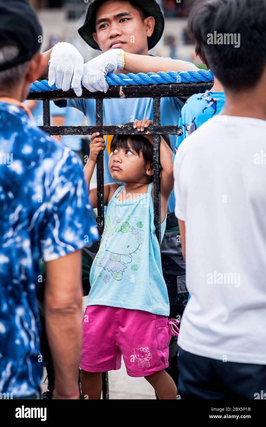 Ein süßes philippinisches Mädchen bekommt bei einer Show während des Feast of the Black Nazarene Festival Manila auf den Philippinen komische Aufmerksamkeit von einem Polizisten. Stockfoto