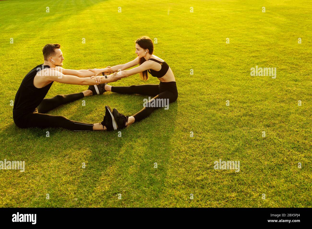 Athletischer Mann und Frau tun verschiedene Übung auf grünem Rasen Stockfoto