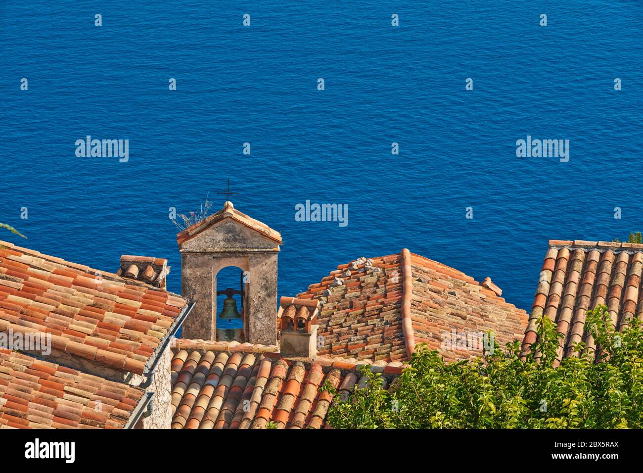 Terracotta Fliesen Dächer und Glockenturm des Dorfes Eze mit dem Mittelmeer. Französische Riviera, Alpes-Maritimes (06), Frankreich Stockfoto