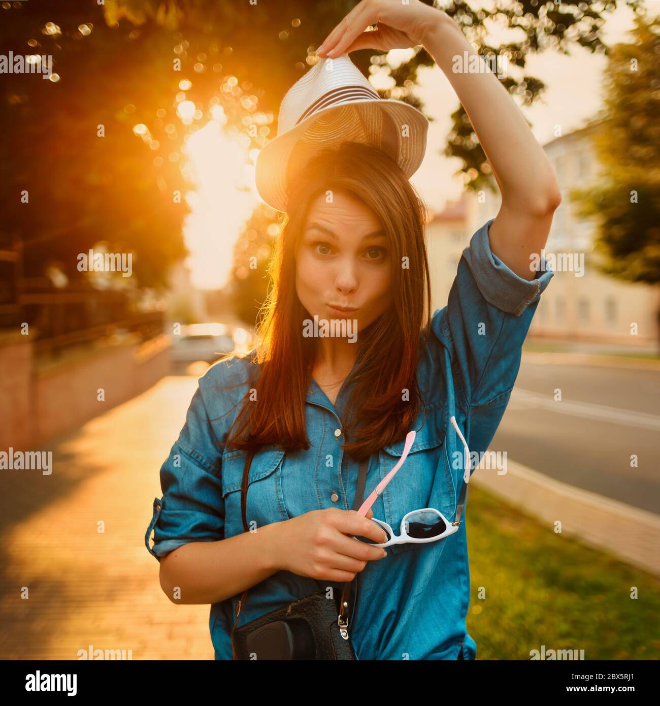 Porträt einer stilvollen Frau in Hut in Morgensonne mit Foto-Kamera Stockfoto