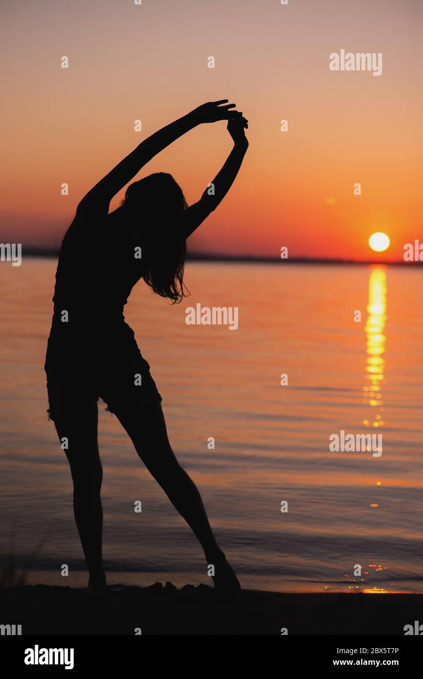 Porträt einer jungen Frau, die am Strand steht und Yoga-Übungen macht Stockfoto