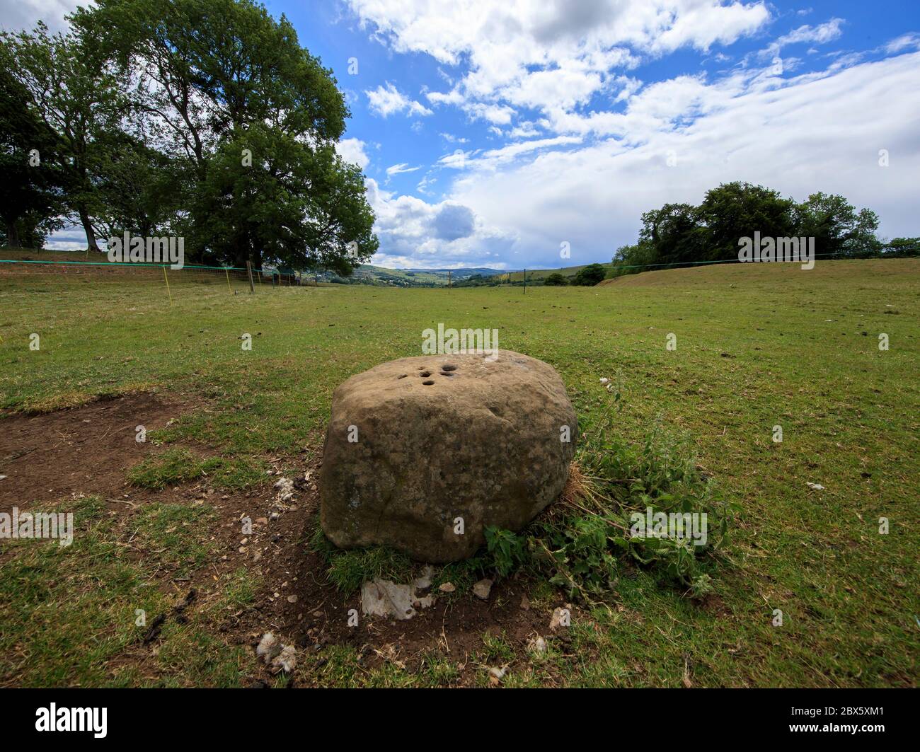 Der Boundary Stone am Rande des Dorfes Eyam in Derbyshire hinterließen die Menschen aus Eyam während der Pest Münzen in Löchern im Stein, die sie mit Essig füllten, in der Hoffnung, die Krankheit zu töten. Benachbarte Gemeindemitglieder hinterließen im Gegenzug Essen. Nachdem im Mai 1666 im Dorf Eyam der erste Fall der Beulenpest gefunden wurde, gingen die Dorfbewohner in eine selbstauferlegte Isolation, um zu verhindern, dass sich die Infektion auf die Nachbargemeinden ausbreitet. Ein Umfang von Steinen umgab das Dorf mit niemand erlaubt, die Grenze in beiden Richtungen bis November 1667 zu überqueren. Stockfoto