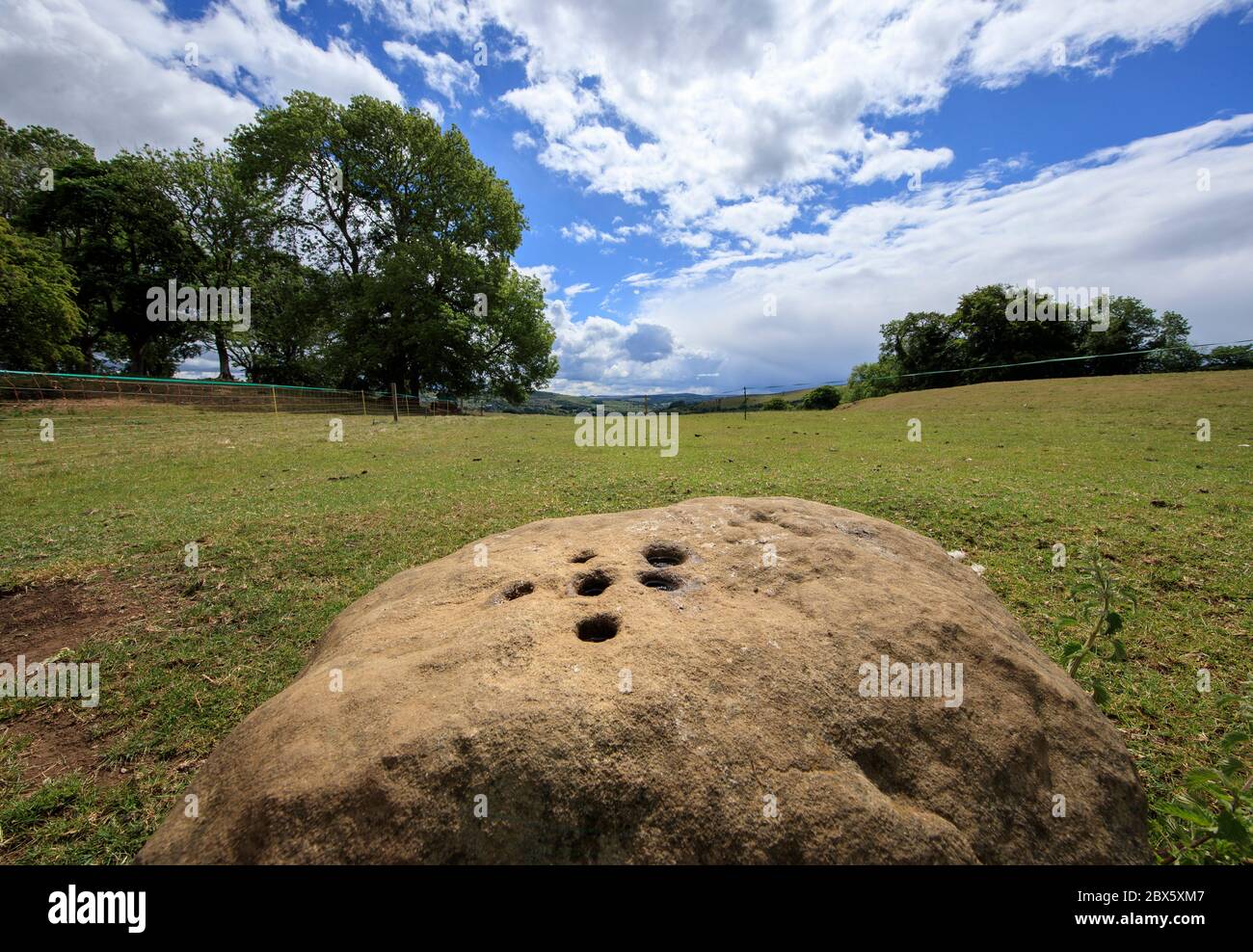 Der Boundary Stone am Rande des Dorfes Eyam in Derbyshire hinterließen die Menschen aus Eyam während der Pest Münzen in Löchern im Stein, die sie mit Essig füllten, in der Hoffnung, die Krankheit zu töten. Benachbarte Gemeindemitglieder hinterließen im Gegenzug Essen. Nachdem im Mai 1666 im Dorf Eyam der erste Fall der Beulenpest gefunden wurde, gingen die Dorfbewohner in eine selbstauferlegte Isolation, um zu verhindern, dass sich die Infektion auf die Nachbargemeinden ausbreitet. Ein Umfang von Steinen umgab das Dorf mit niemand erlaubt, die Grenze in beiden Richtungen bis November 1667 zu überqueren. Stockfoto