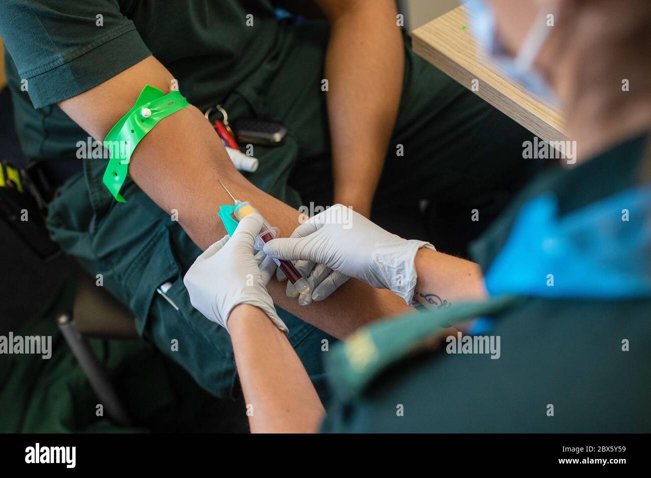 Ein Sanitäter (rechts) nimmt während eines Coronavirus-Antikörpertestprogramms im Hollymore Ambulance Hub des West Midlands Ambulance Service in Birmingham eine Blutprobe von einem medizinischen Mitarbeiter. Stockfoto