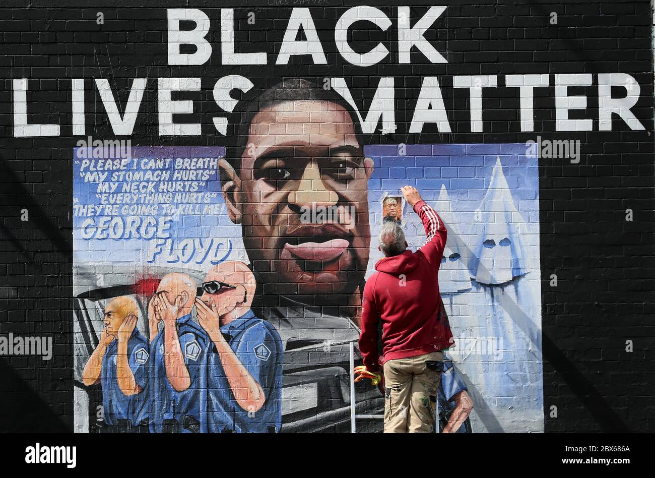 BEACHTEN SIE GRAFISCHE INHALTE AUF WANDBILD Künstler Micky Doc entfernt ein Foto, das verwendet wird, um ein Wandbild zu George Floyd an der Belfast International Wall an der Falls Road zu malen. Herr Floyd wurde am 25. Mai in Polizeigewahrsam in der US-Stadt Minneapolis getötet. Das Wandgemälde wurde von Feile an Phobail und Failte Feirste Thiar in Auftrag gegeben und von Marty Lyons und Micky Doherty gemalt. Stockfoto