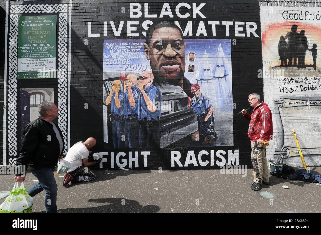 BEACHTEN SIE GRAFISCHE INHALTE AUF WANDMALEREI die Künstler Lyonsie (zweite links) und Micky Doc setzen den letzten Schliff zu einem Wandgemälde von George Floyd an der Belfaster International Wall an der Falls Road. Herr Floyd wurde am 25. Mai in Polizeigewahrsam in der US-Stadt Minneapolis getötet. Das Wandgemälde wurde von Feile an Phobail und Failte Feirste Thiar in Auftrag gegeben und von Marty Lyons und Micky Doherty gemalt. Stockfoto