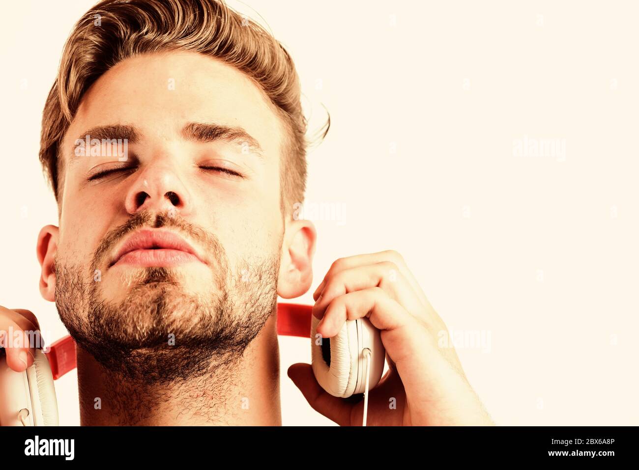 Mann schön unrasiert Hipster hören über Kopfhörer song Gadget weißen Hintergrund. Sehr gute moderne Ausstattung. Jeder Sound genießen. Moderne Ohrhörer. Reiner Klang. Inspirierende Musik Konzept. Stockfoto