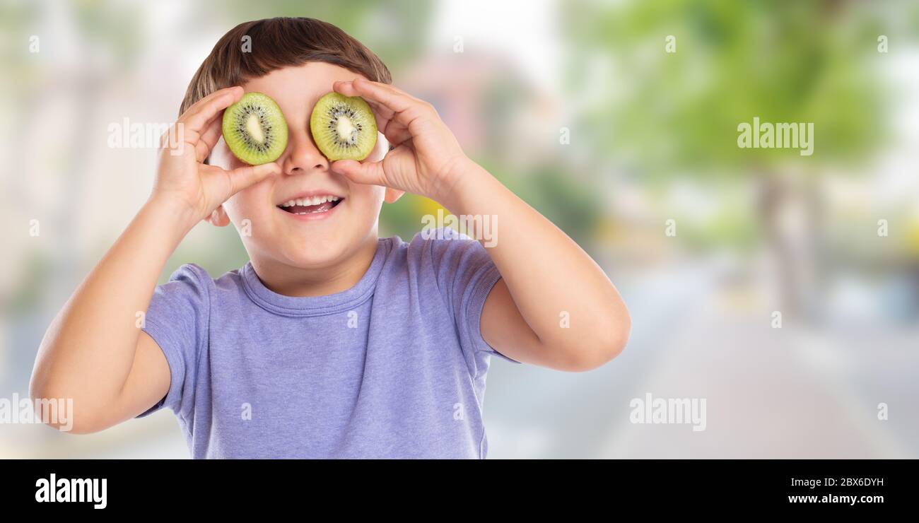 Kind kleiner Junge mit Kiwi Obst Spaß Banner Copyspace kopieren Raum Stadt glücklich Glück gesunde Ernährung im Freien Stockfoto