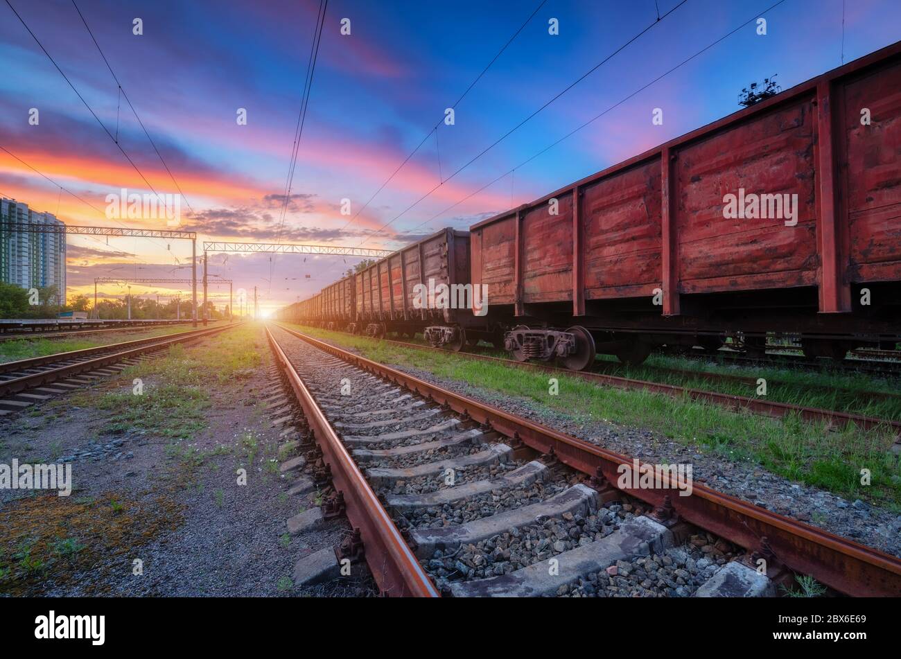 Bahnhof mit Güterzügen bei buntem Sonnenuntergang Stockfoto