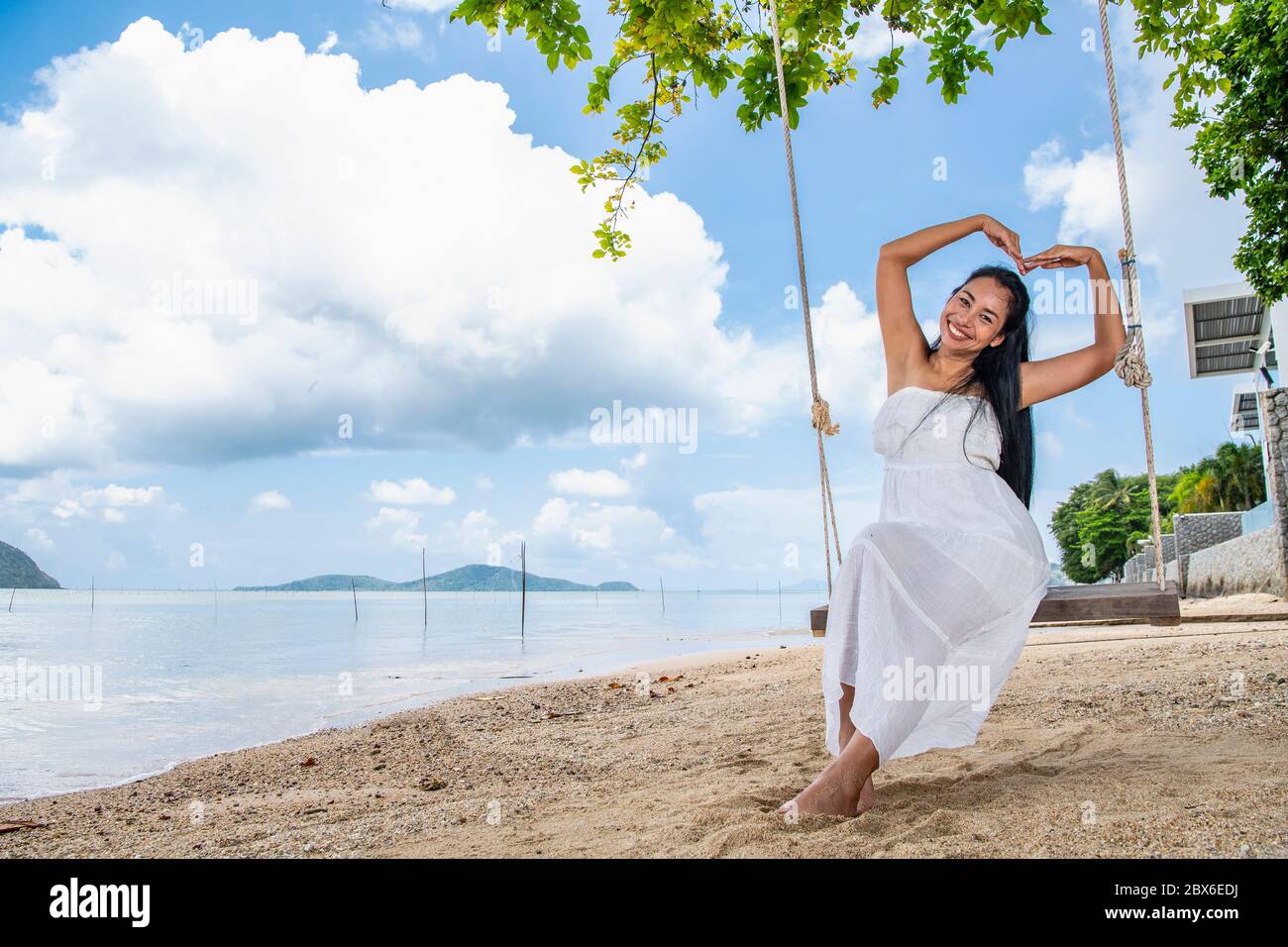 Schöne Frau, die auf einer Schaukel am Strand sitzt Phuket Stockfoto