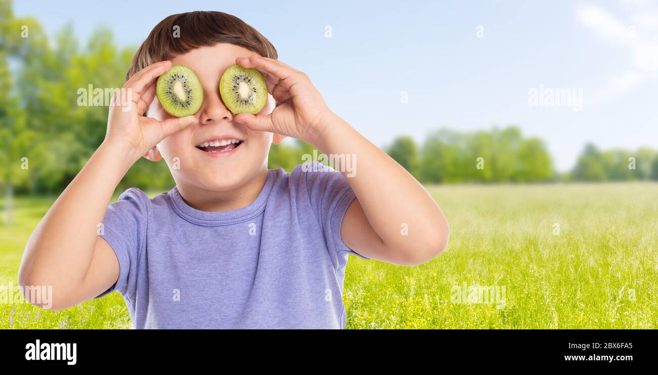 Junges Kind kleiner Junge Kiwi Obst Spaß Banner Copyspace kopieren Raum im Freien glücklich Glück gesunde Ernährung im Freien Stockfoto