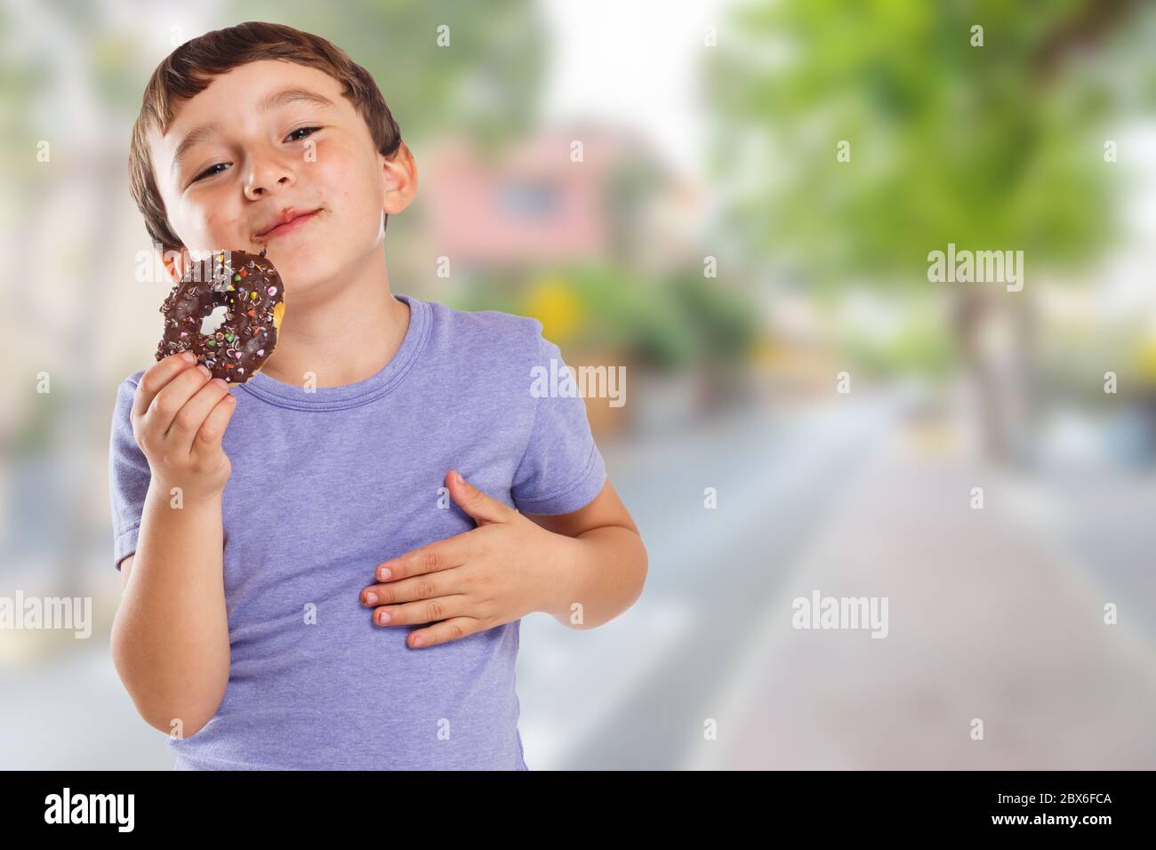 Junge Kind essen Donut Stadt Kopierer Raum ungesunde süße Süßigkeiten im Freien Stockfoto