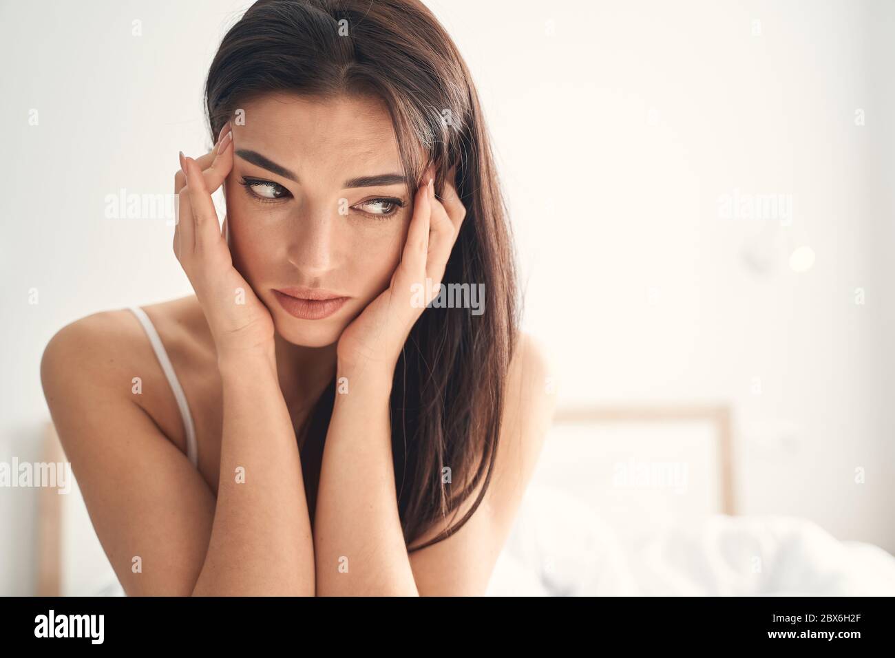 Junge Frau, die morgens Kopfschmerzen hat Stockfoto