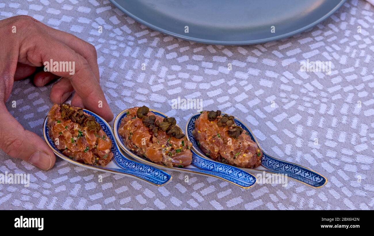 Lachsfleisch mit Gewürzen auf dem Tisch. Das Fleisch wird dekorativ in keramischen Löffeln präsentiert. Stockfoto