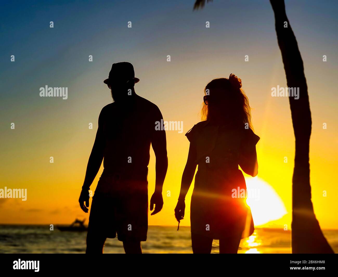 Paares Silhouette am Strand bei Sonnenuntergang mit Boot im Hintergrund. Grand Bahia Principe Strand in Punta Cana, Dominikanische Republik. Stockfoto