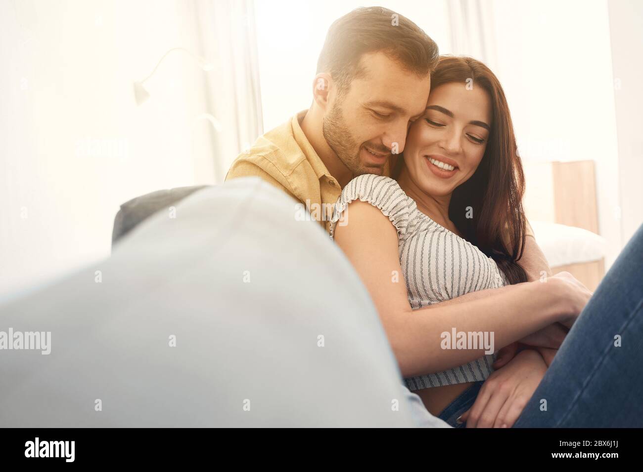 Glückliche Brautpaare halten sich gegenseitig mit den Händen auf einem Sofa Stockfoto