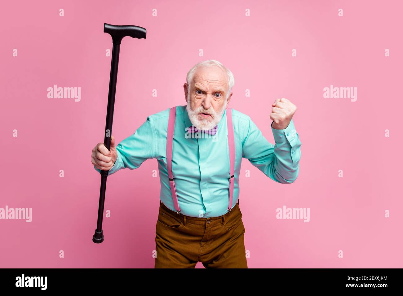 Halt den Mund. Foto von aggressiven gealterten Mann heben Walking Stock Faust wütend Grimace Schuld Nachbar Kinder für Lärm tragen Hemd Hosenträger Fliege Hose Stockfoto