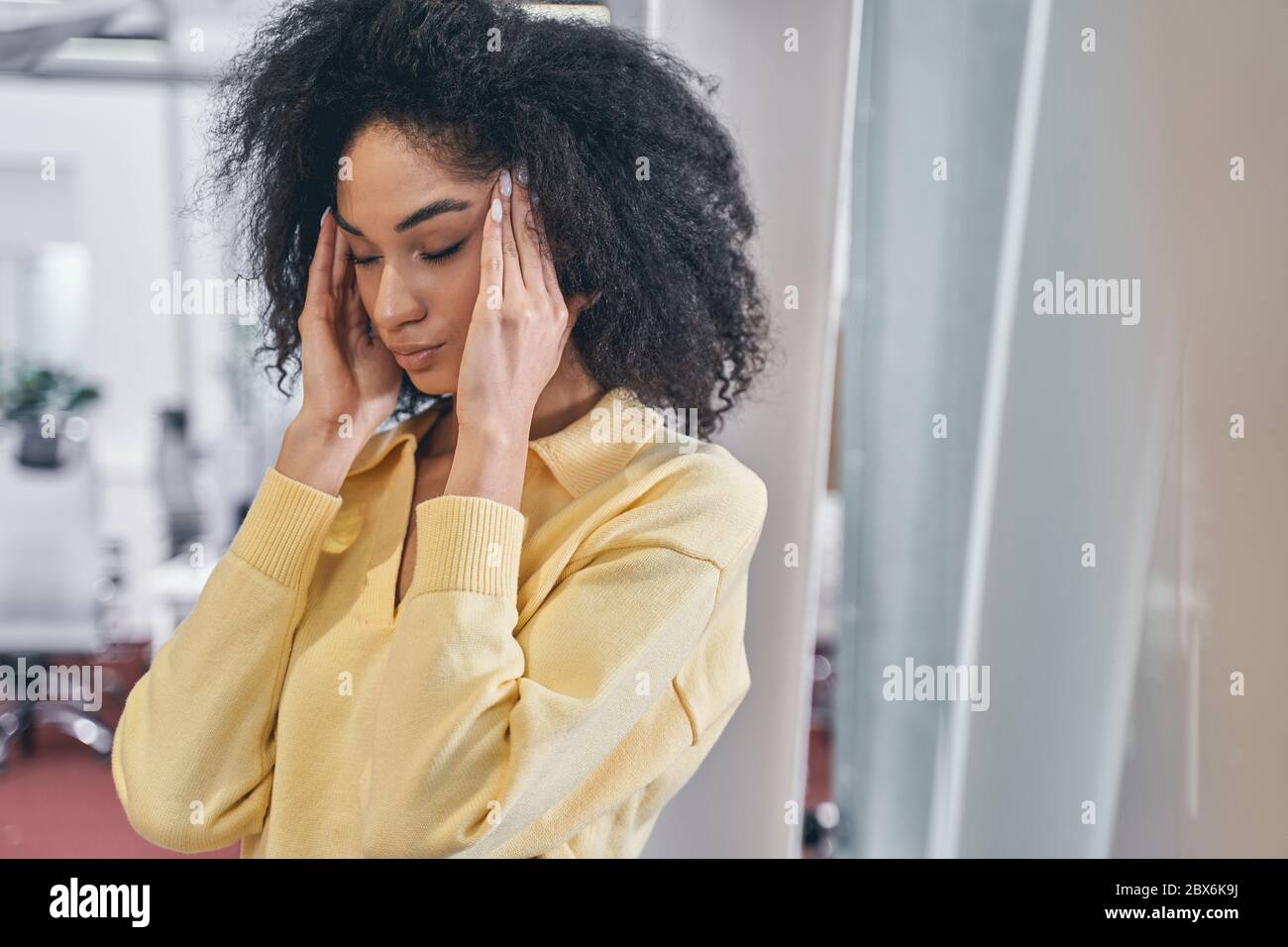 Junge moderne Angestellte, die Kopfschmerzen hat Stockfoto