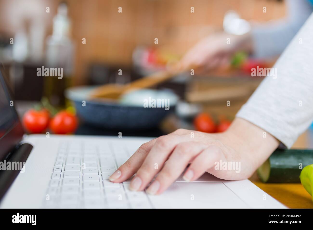 Frau Kochen gesunde Mahlzeit. Food Blog Konzept. Multitasking von zu Hause aus. Stockfoto