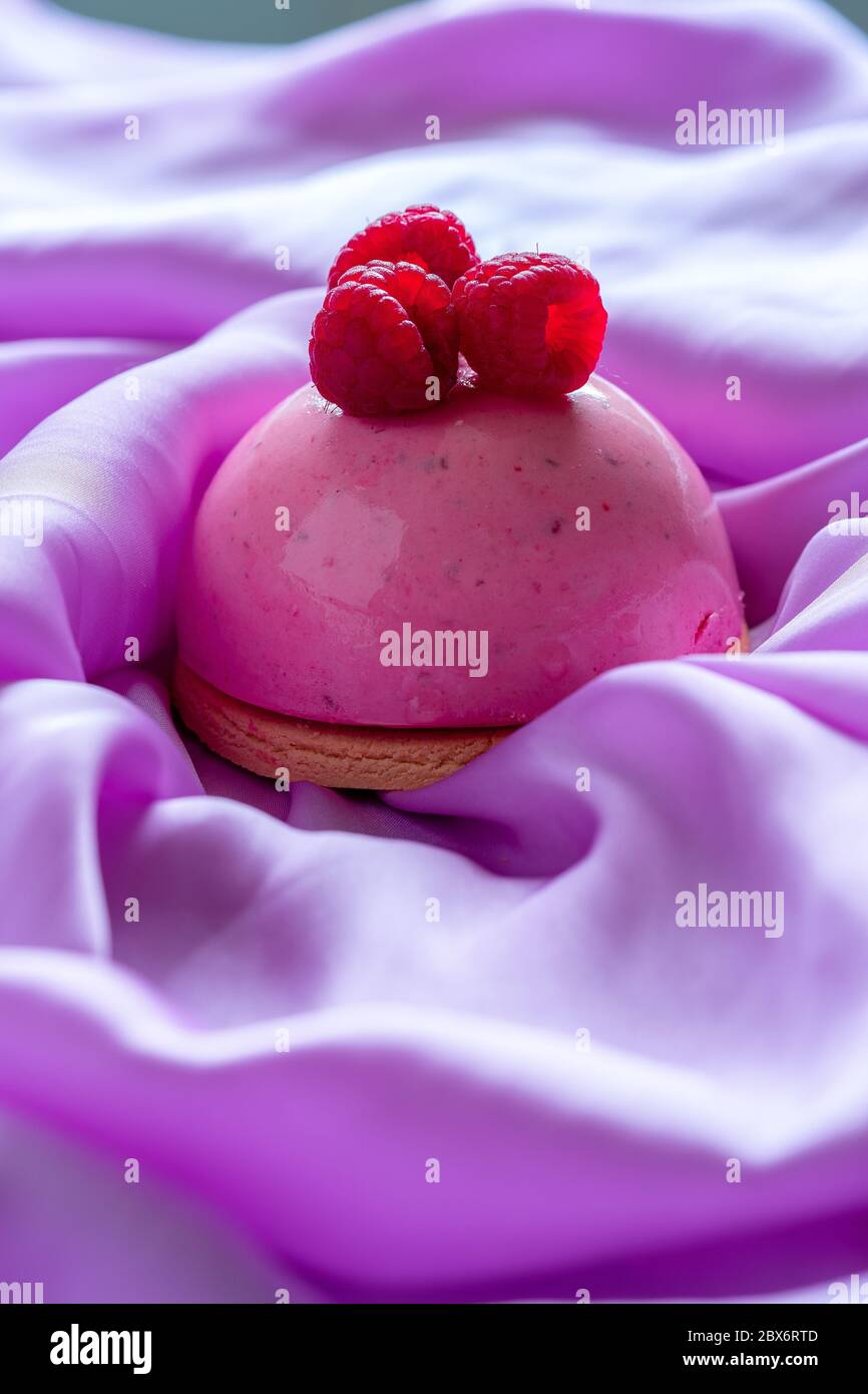 Himbeer-Mousse Tartlet von frischen köstlichen Himbeeren auf Hell Violet Seide Tuch Hintergrund dekoriert. Berry Dessert Kalorienarm. Diät Halten. Stockfoto