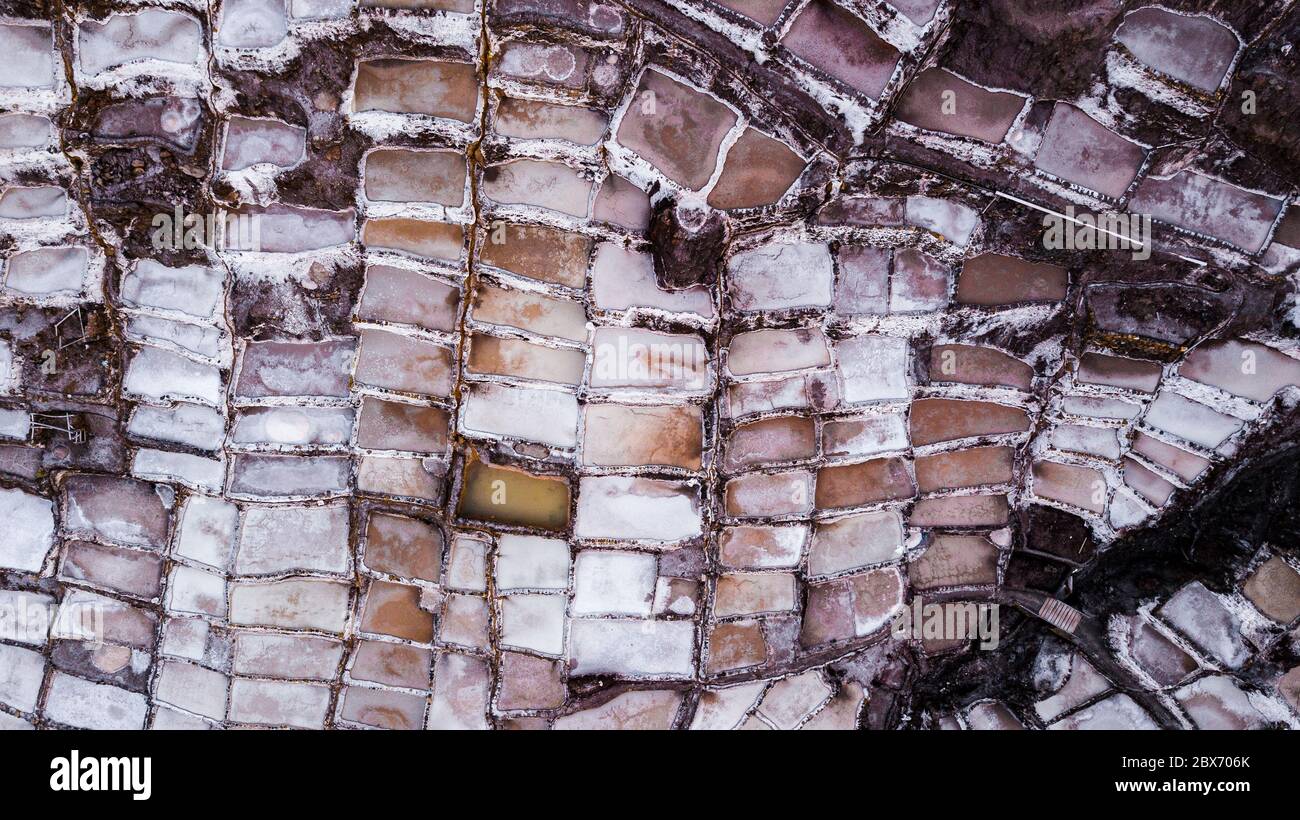 Luftaufnahme von Salzverdunstungsteichen in einer Salzmine in Maras, Peru. Verschiedene Formen und Farben von Teichen erzeugen abstrakte Muster und Formen. Stockfoto