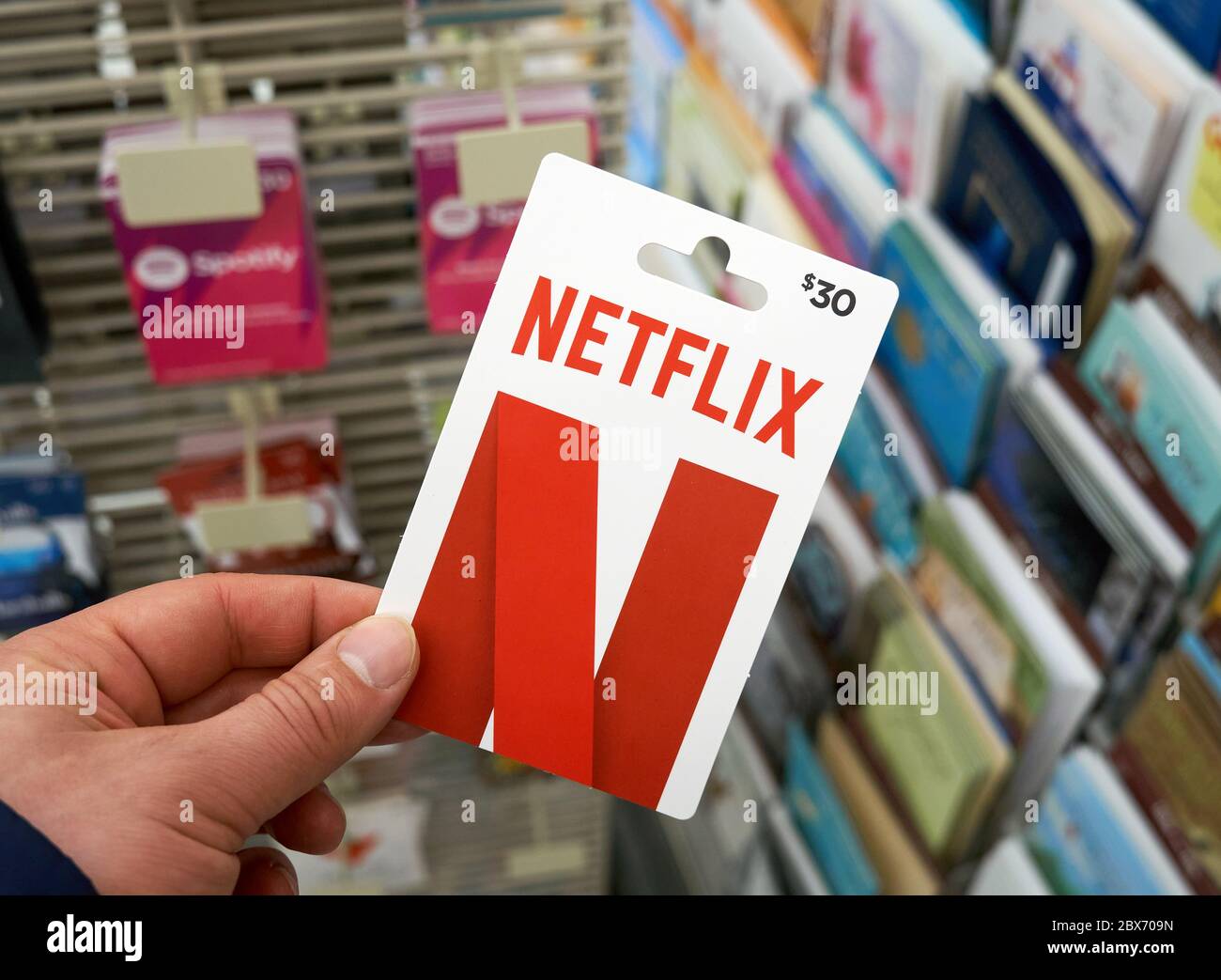 Montreal, Kanada - 03. Mai 2020: Netflix-Geschenkkarte in einer Hand über einem Ständer mit Geschenkkarten. Netflix ist ein Streaming-Dienst, der Fernsehsendungen ansehen kann Stockfoto