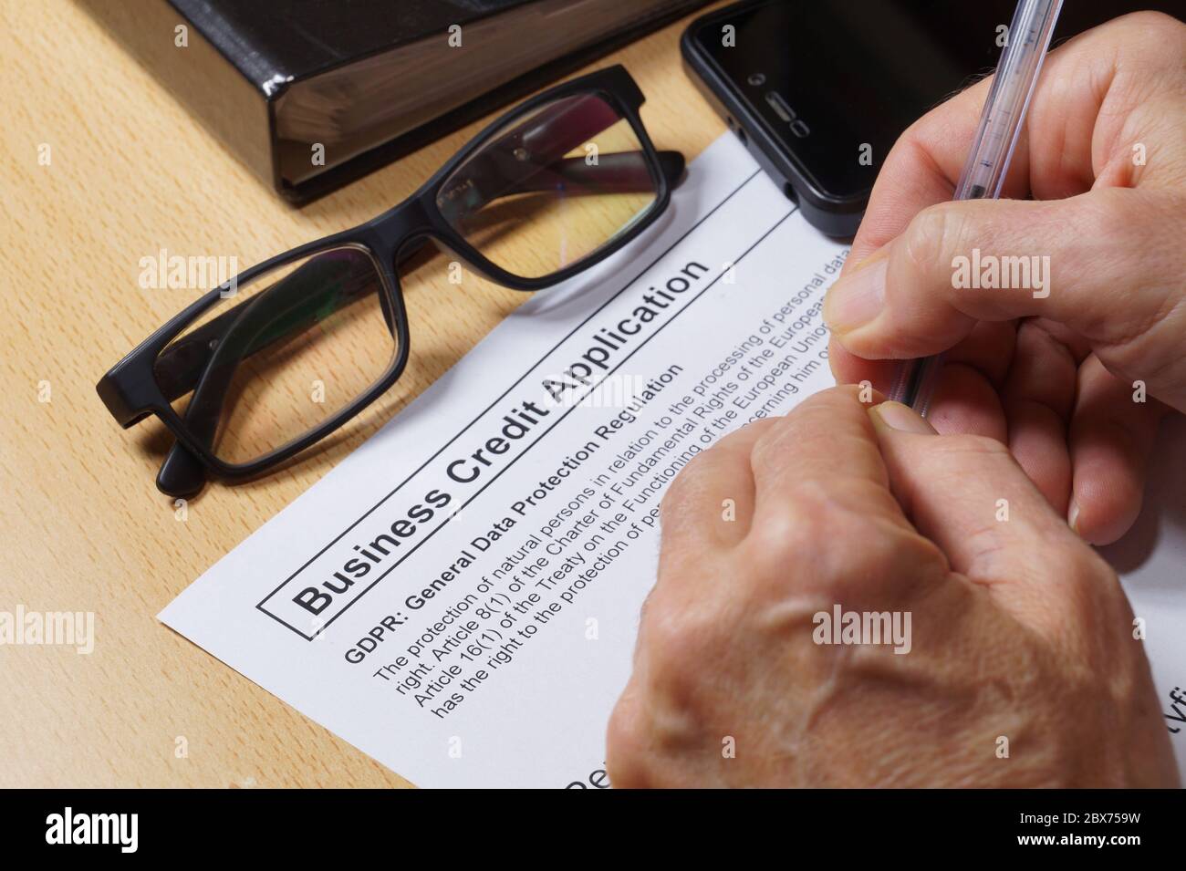 Antrag auf Unternehmenskredit. Ein Mann füllen ein Formular mit einer DSGVO-Klausel (Datenschutz-Grundverordnung) aus. Stockfoto