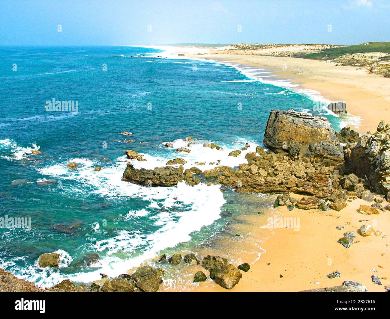 Goldener, endloser Strand und blaues Wasser im Atlantik mit Brandung in Sines, Portugal. Stockfoto