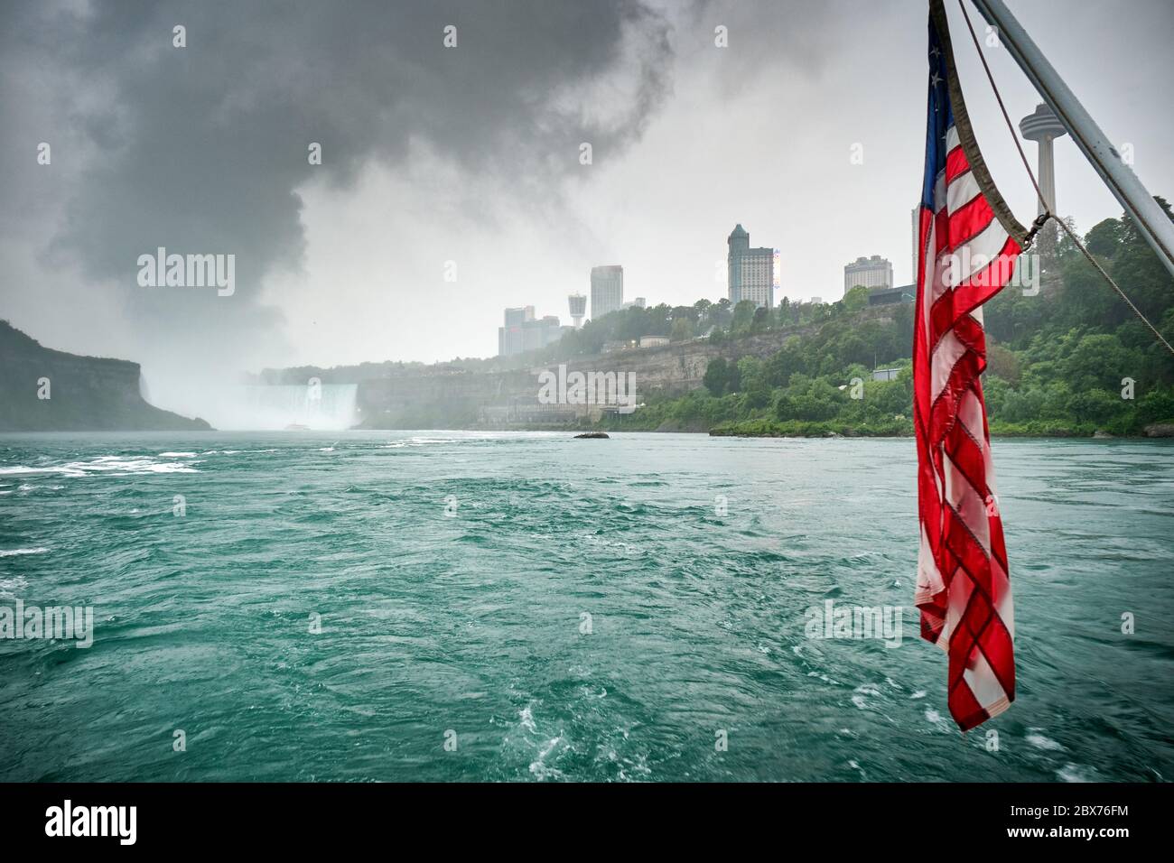 Flagge der Vereinigten Staaten mit den Niagarafällen im Hintergrund, bewölktem Tag und surrealer Atmosphäre Stockfoto