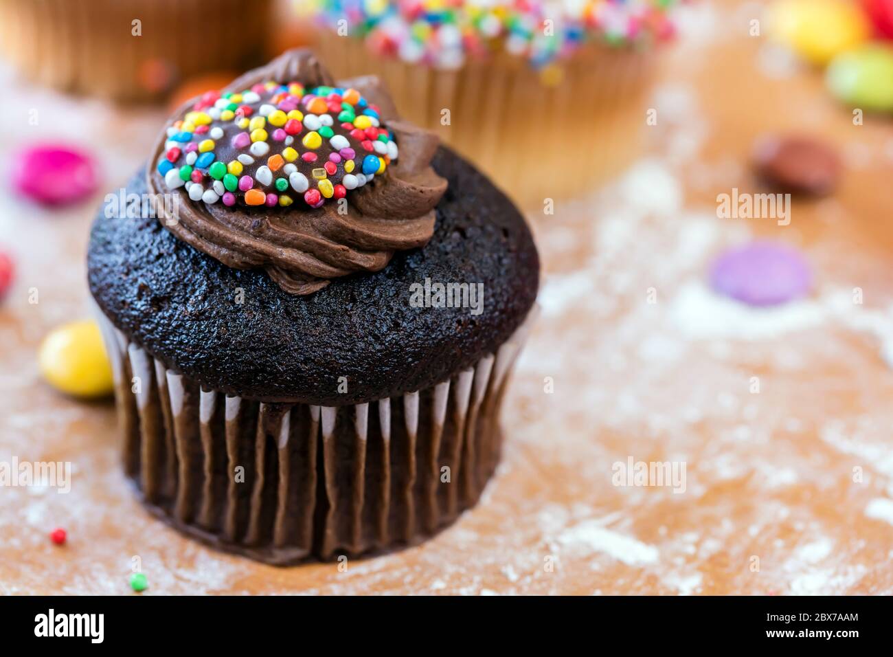 Schokoladenkuchen mit Zuckerguss und Streuseln, auf bemehltem Brett. Stockfoto