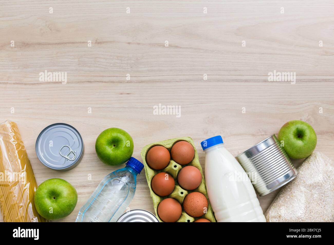 Charity Spende Lebensmittel-Set: Öl, Obst, Getreide, Konserven. Holzküchentisch Hintergrund in skandinavischen Interieur. Flatlay, Draufsicht. Speicherplatz kopieren Stockfoto