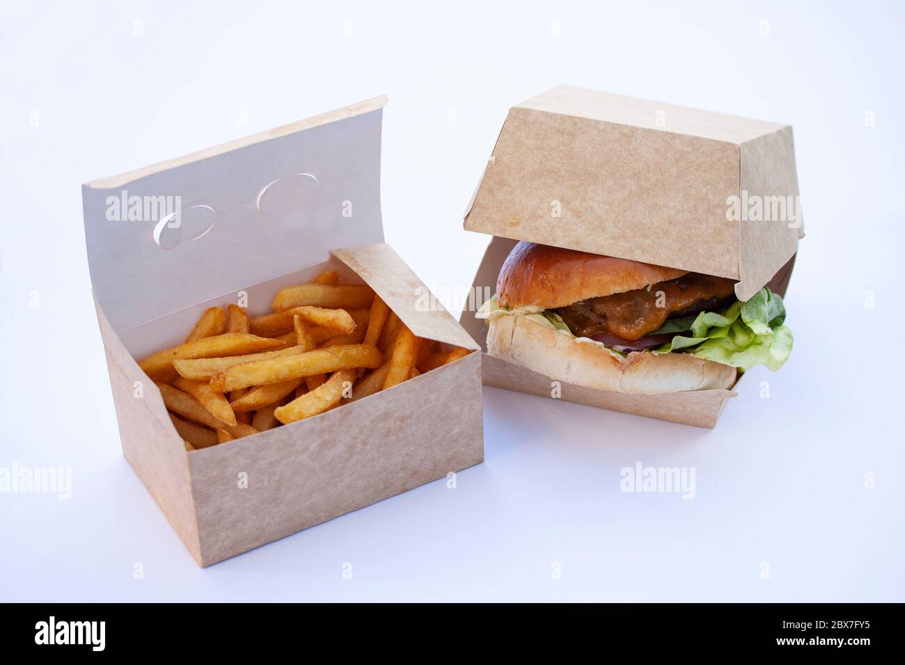 Leckere knusprige pommes Frites und ein großer saftiger Burger. In offenen Boxen aus nachhaltiger Pappe. Auf weißem Hintergrund. Stockfoto