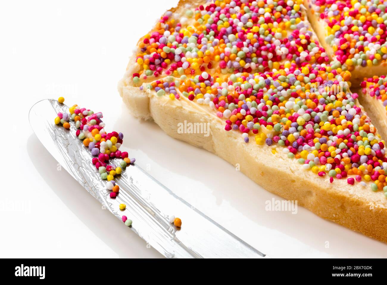 Fairy Bread mit Buttermesser, Seitenansicht. Traditionelles australisches Kinderparty-Essen, Hunderte und Tausende Süßigkeiten bestreuen Weißbrot. Stockfoto