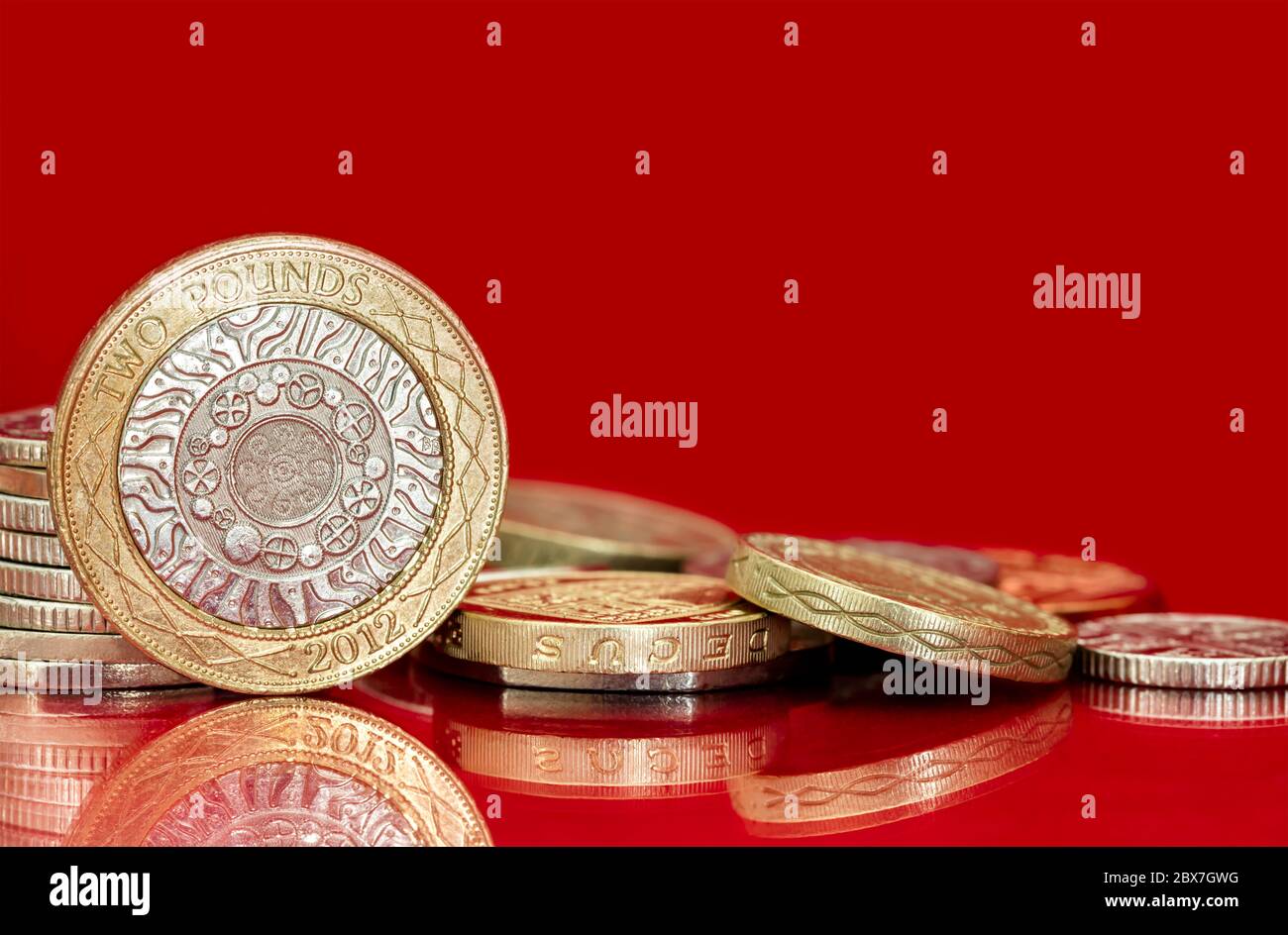 Britische Münzen auf hellrotem Hintergrund. Viel Kopierplatz. Stockfoto