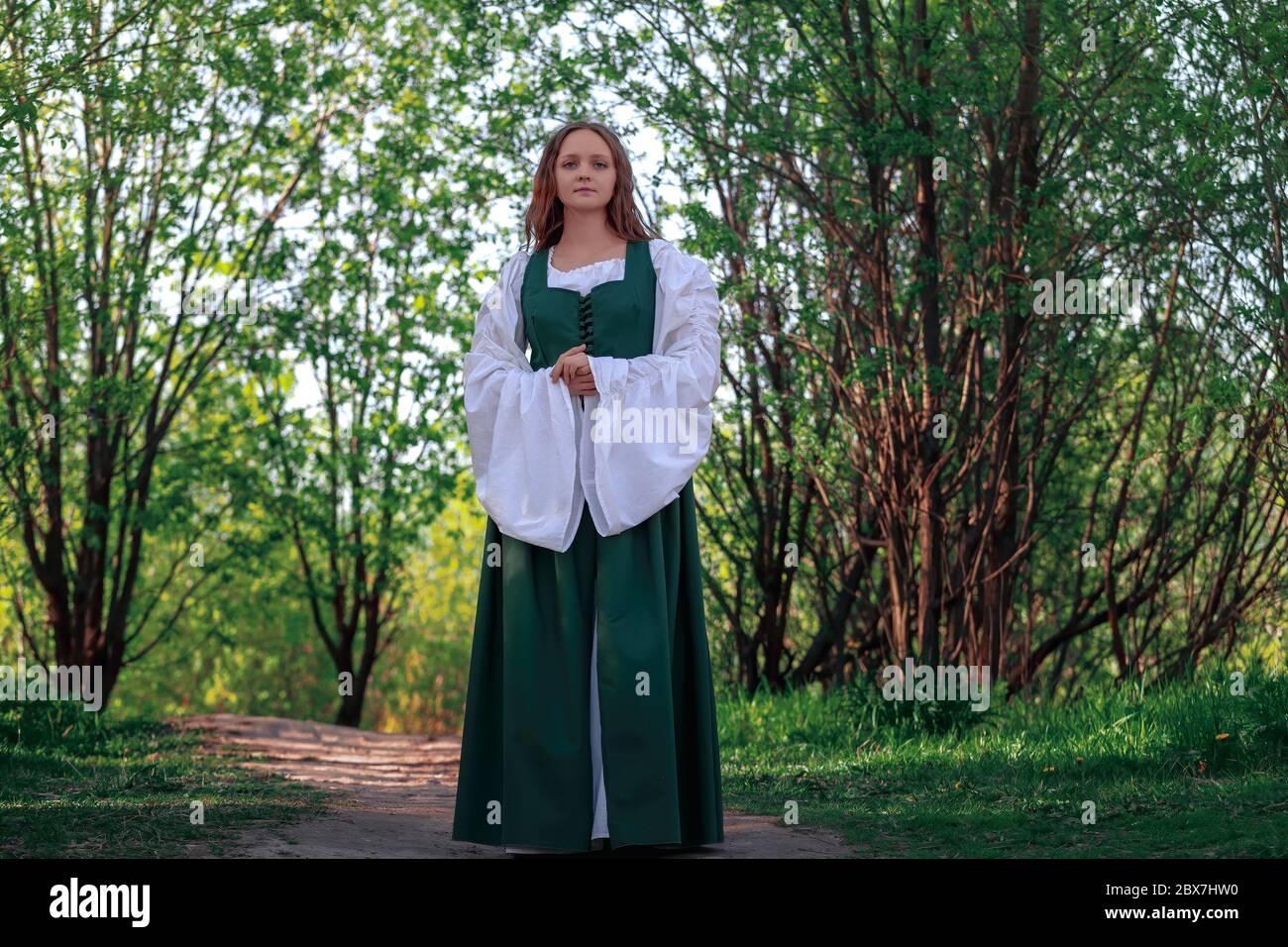 Schöne mittelalterliche junge Frau in traditionellen historischen weiblichen grün und weiß Kostüm in der Natur. Fantasy-Mädchen in langen Kleid oder Kleid zu Fuß auf dem Weg Stockfoto