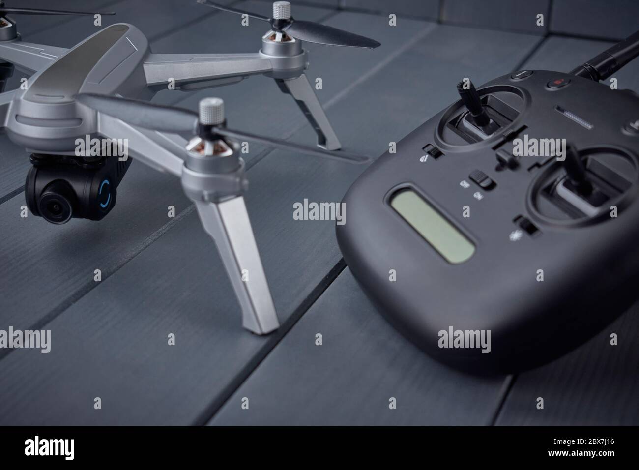 Nahaufnahme der Quad-Engine Drohne montiert Kamera und Dual-Frequenz-Funkfernbedienung im Hintergrund auf grauem Holzhintergrund Stockfoto