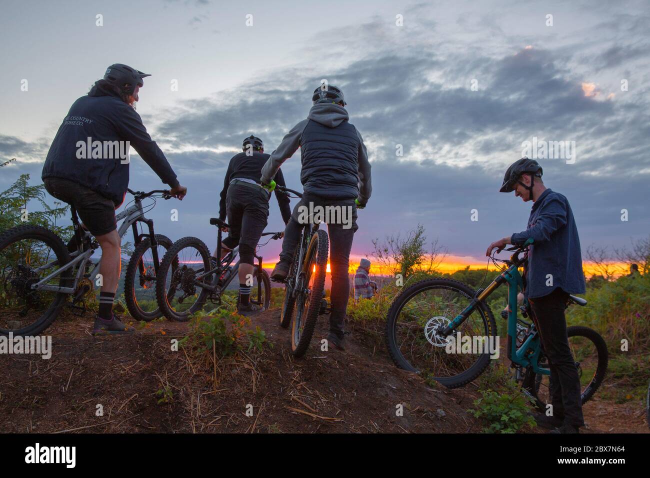 Mountainbiker treffen sich auf dem Hügel bei Sonnenuntergang in Großbritannien Stockfoto