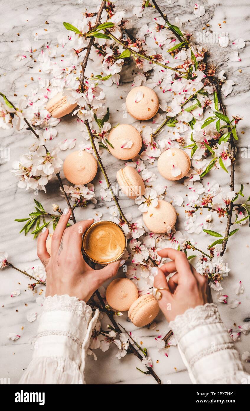Die Hände der Frauen halten frischen Kaffee und Makronen Stockfoto