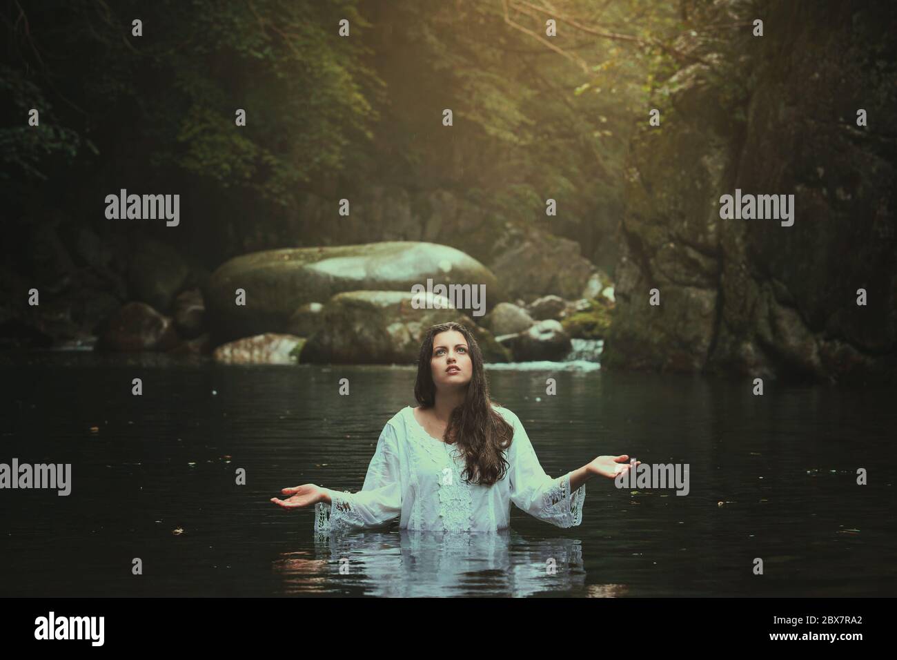 Schöne junge Frau in einem Bergbach beten. Fantasie und Surreal Stockfoto