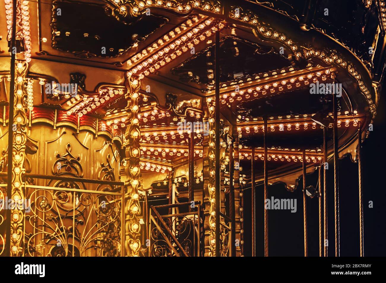 Foto eines aufgehellten goldenen Karussells mit roten und gelben Lichtblenden in der Nahaufnahme. Stockfoto