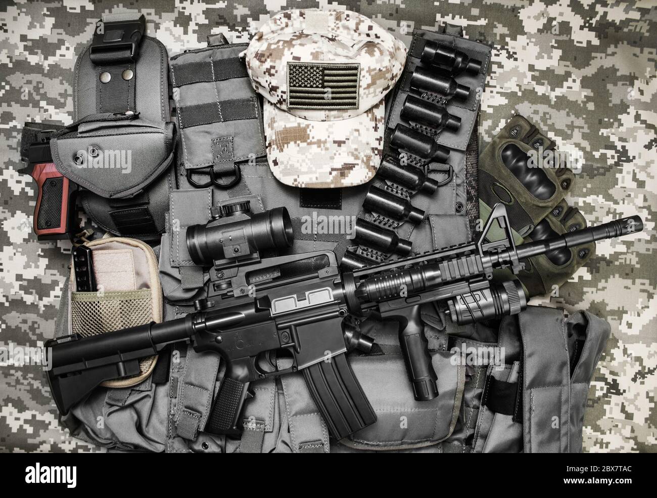 Foto einer taktischen Weste, Gewehr, Pistole, Hut mit amerikanischer Flagge Abzeichen und cartrige Gürtel auf Tarnhintergrund. Stockfoto