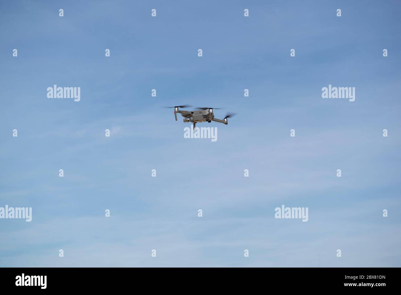 Drohne fliegt in blauem Himmel mit Wolken im Hintergrund. Drohne fliegt über dem Himmel in wolkig-blauem Himmel. Drohne Quad Copter mit hochauflösender digitaler Kamera Stockfoto